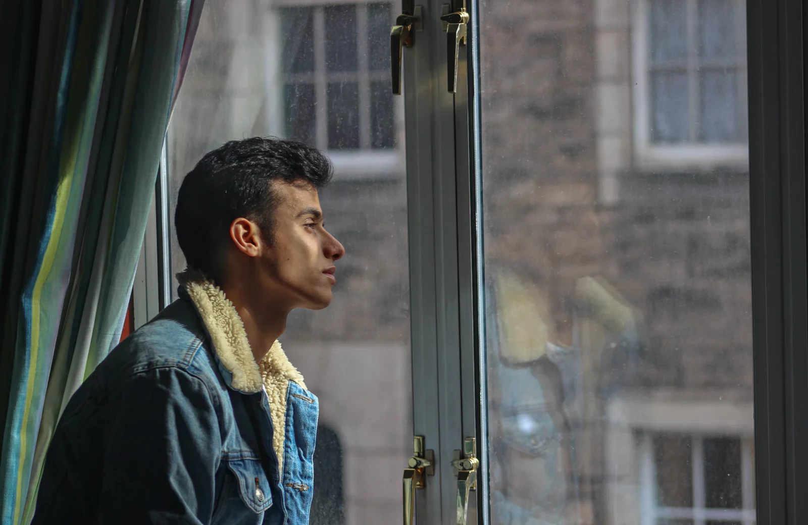Person looking thoughtfully through a window