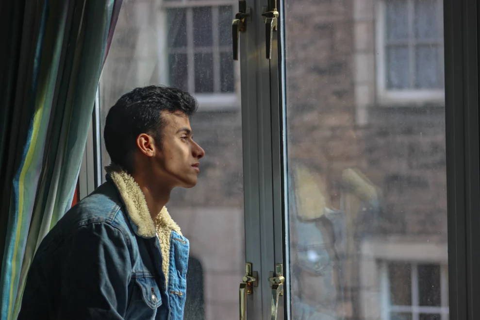 Person looking thoughtfully through a window